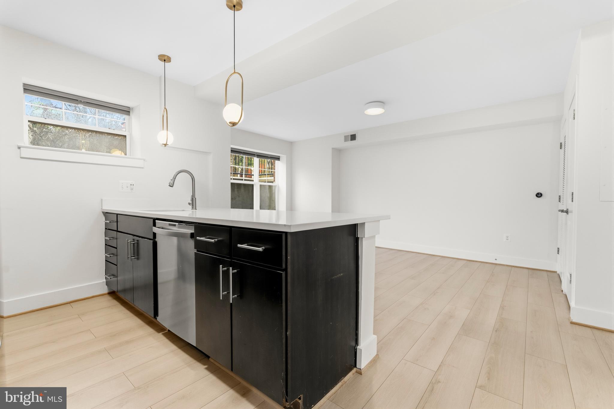 4226 7th Street Northwest, Unit 101 Washington, DC 20011 - Photo 5 of 23 a kitchen with kitchen island a sink stainless steel appliances and cabinets