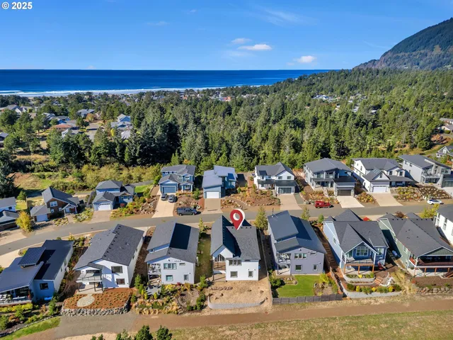 an aerial view of a city with lots of residential buildings ocean and mountain view in back