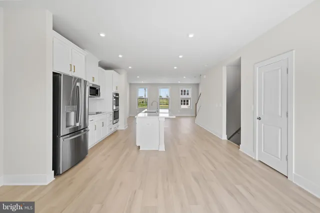 a view of an empty room with wooden floor and stairs