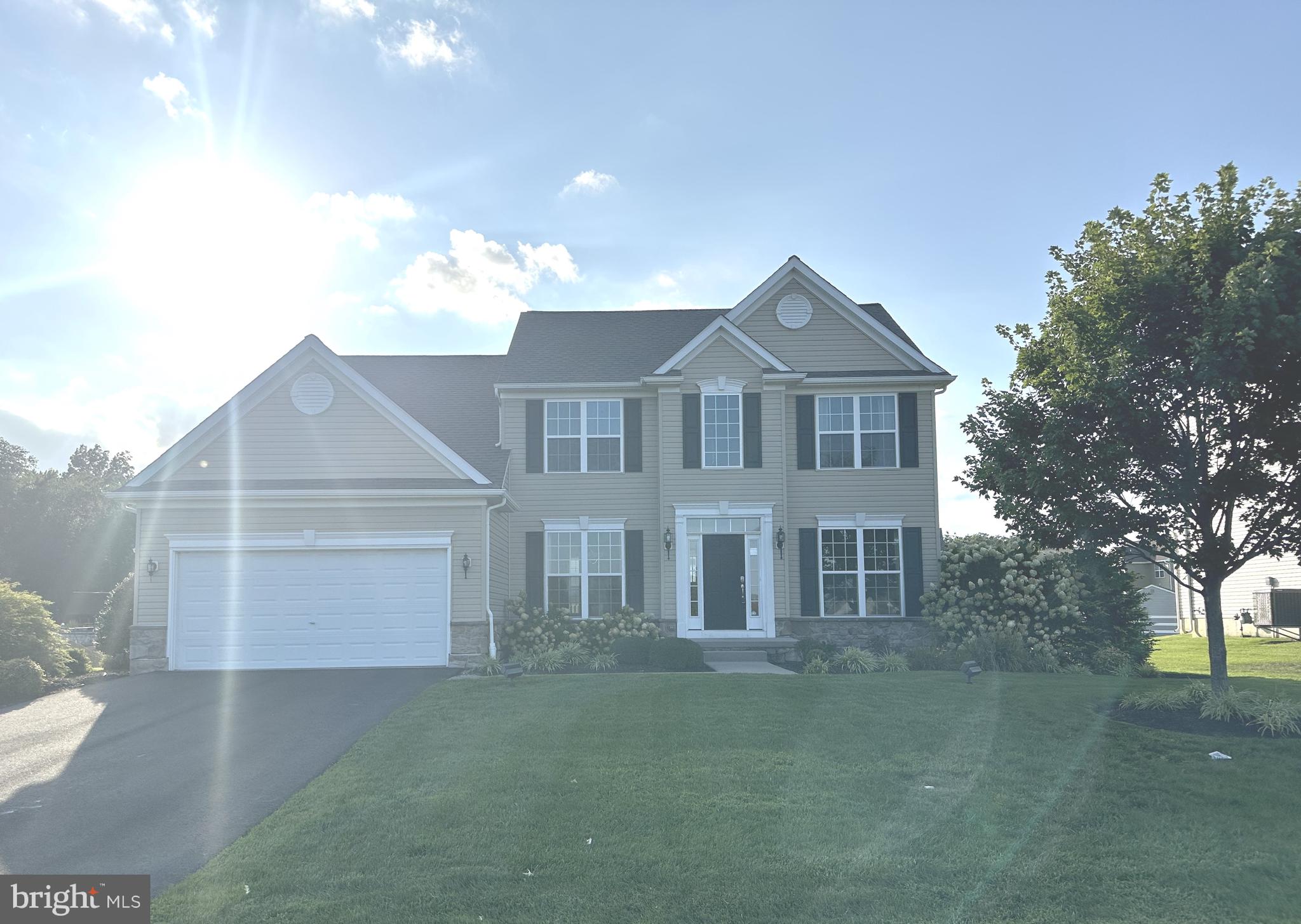a front view of a house with a garden and trees