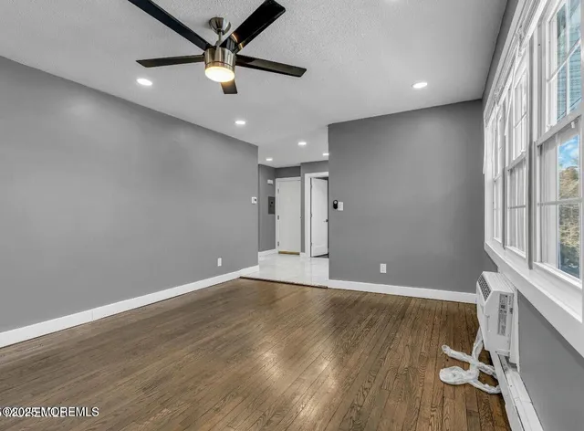 an empty room with wooden floor and a ceiling fan