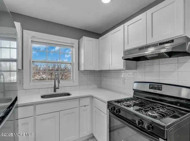 a kitchen with stainless steel appliances granite countertop white cabinets and a stove top oven