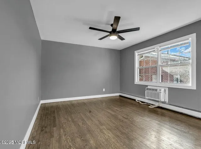 an empty room with wooden floor fan and windows