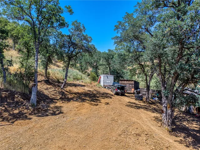 a view of a house with large trees and sitting area