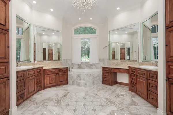 a large bathroom with a granite countertop double vanity sink a mirror and a bathtub