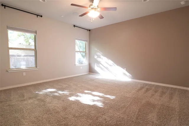 en empty room with windows and chandelier fan
