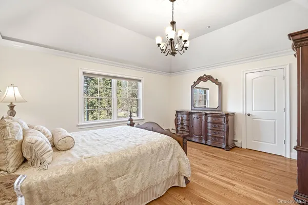 a bedroom with a large bed a chandelier and a dresser