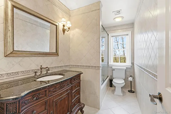 a bathroom with a granite countertop sink a toilet and a mirror