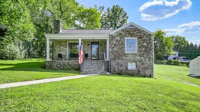 a view of a brick house with a big yard and large trees
