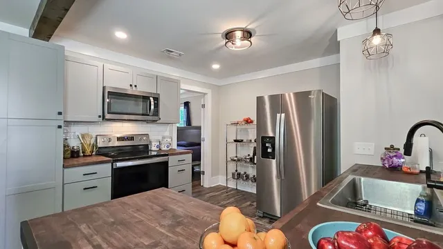 a kitchen with stainless steel appliances granite countertop a refrigerator a stove a sink dishwasher a dining table and chairs with wooden floor