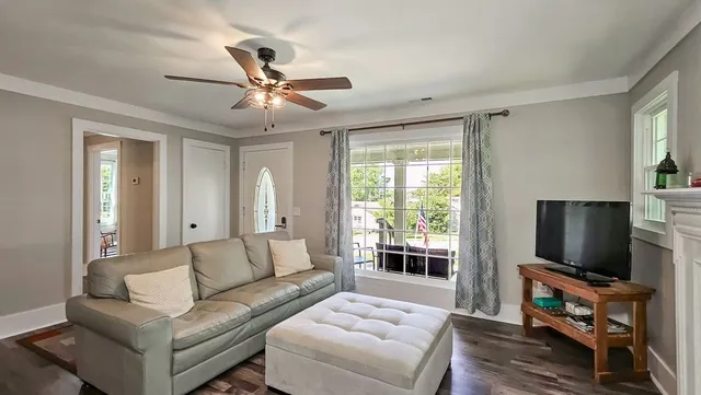 a living room with furniture a ceiling fan and a flat screen tv