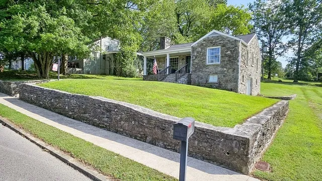 a view of a house with a yard and a large tree