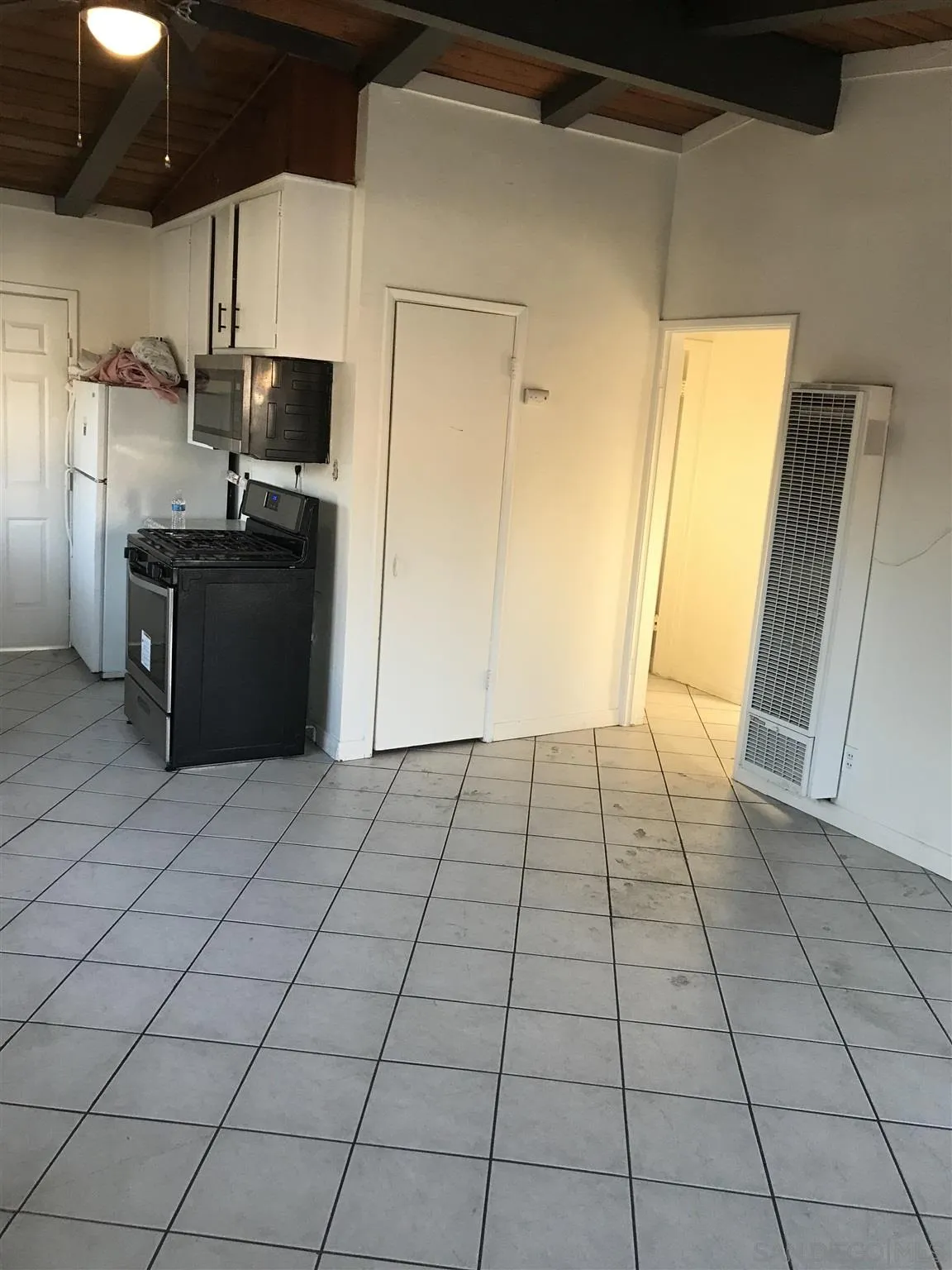 395-397 Eddie Drive Vista, CA 92083 - Photo 19 of 30 a view of a refrigerator in kitchen and an empty room with wooden floor