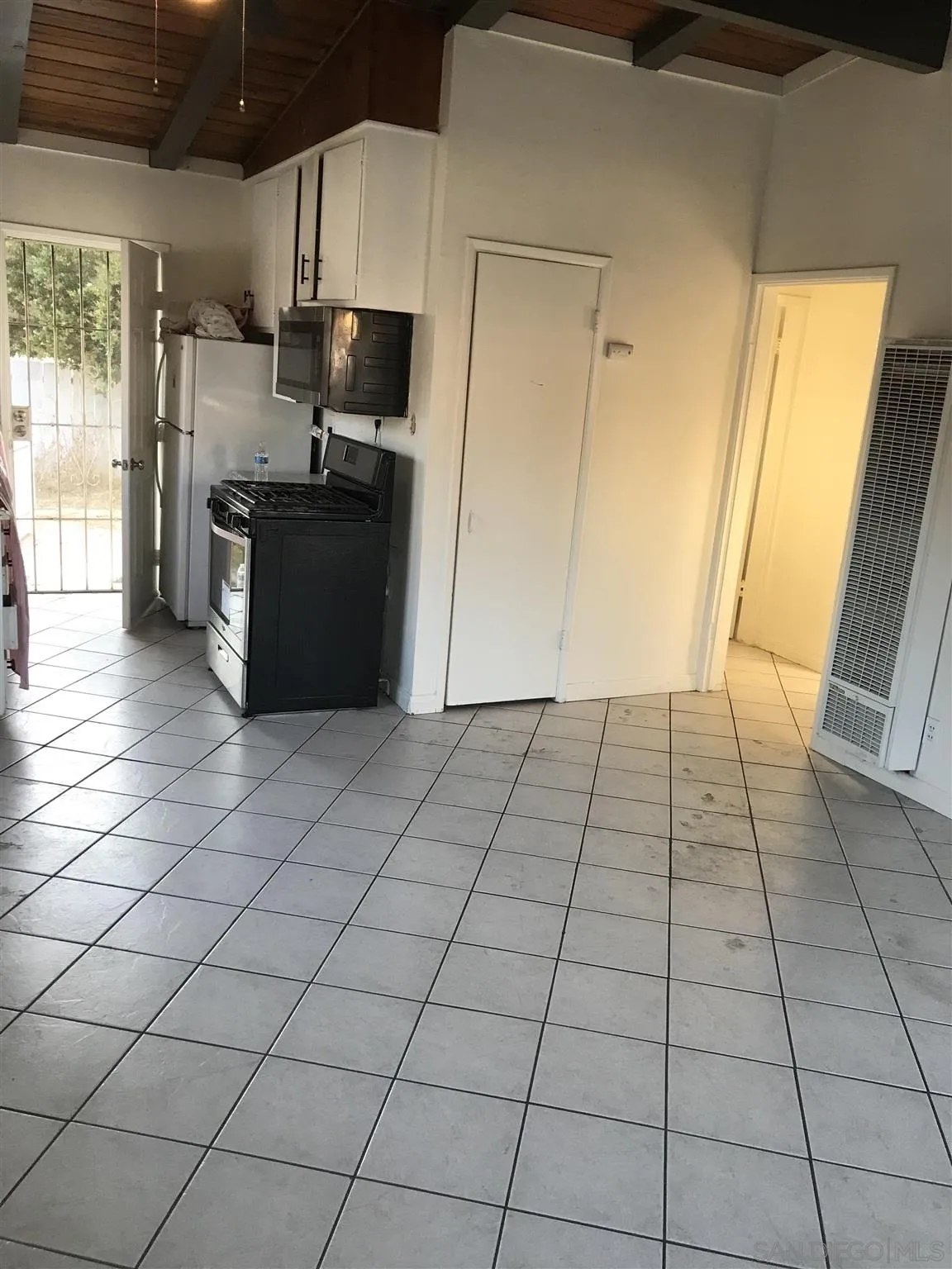 395-397 Eddie Drive Vista, CA 92083 - Photo 29 of 30 a view of a refrigerator in kitchen and an empty room and wooden floor