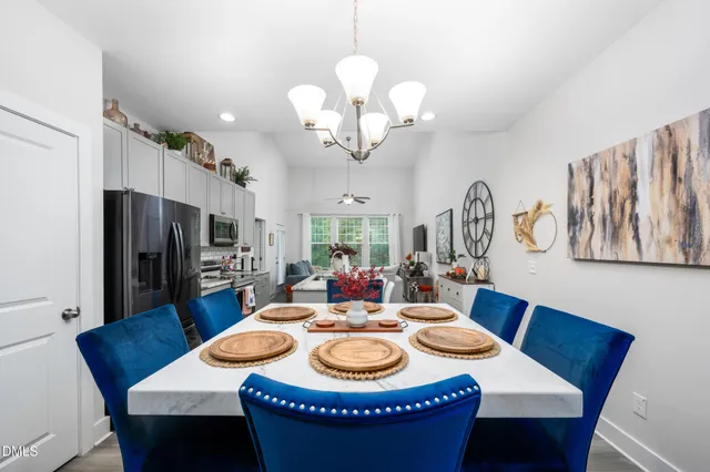 a dining room with wooden floor a chandelier a wooden table and chairs