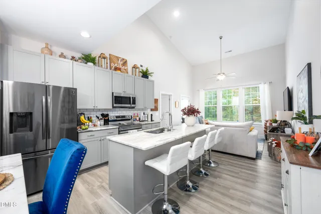 a kitchen with stainless steel appliances a dining table chairs stove refrigerator and microwave