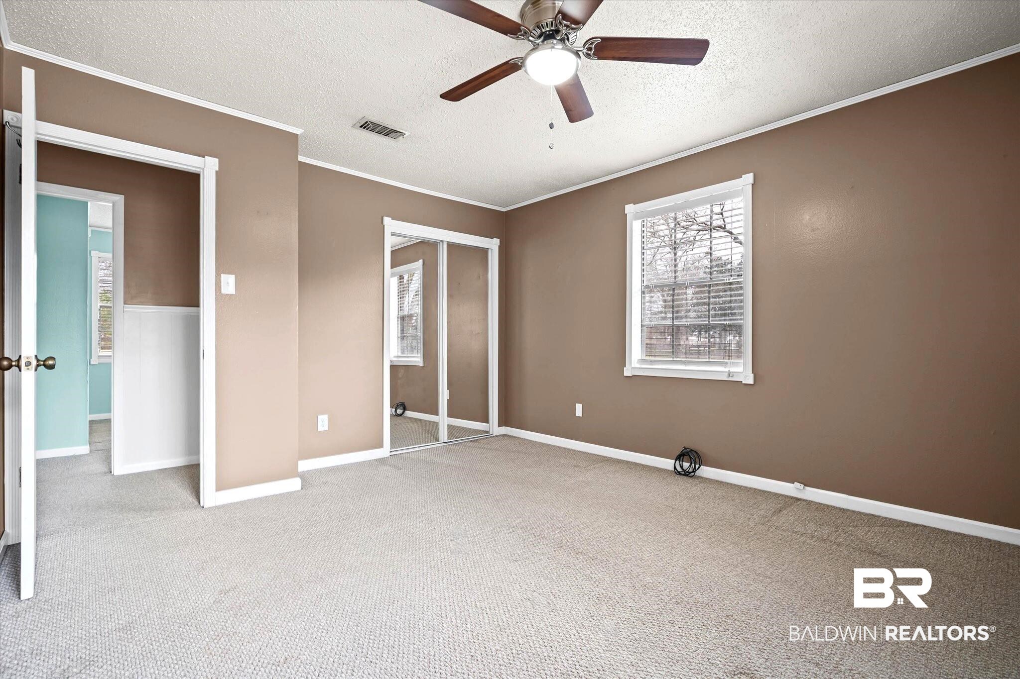 8090 Murray Hill Road Irvington, AL 36544 - Photo 27 of 40 Unfurnished bedroom featuring a textured ceiling, light colored carpet, crown molding, a closet, and a ceiling fan