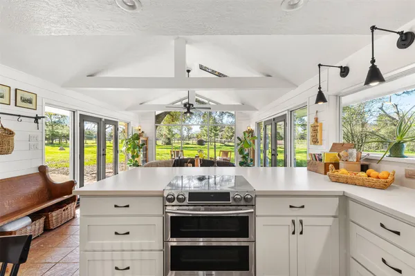 a kitchen with a stove a refrigerator and a view of living room