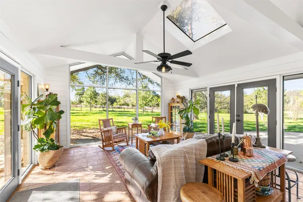 a living room with furniture a ceiling fan and a large window