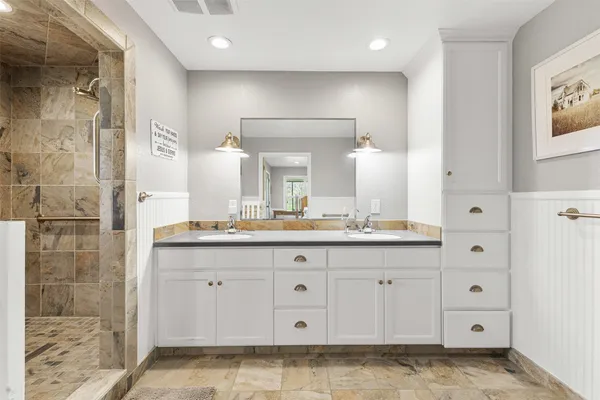 a bathroom with a granite countertop sink a mirror and a shower