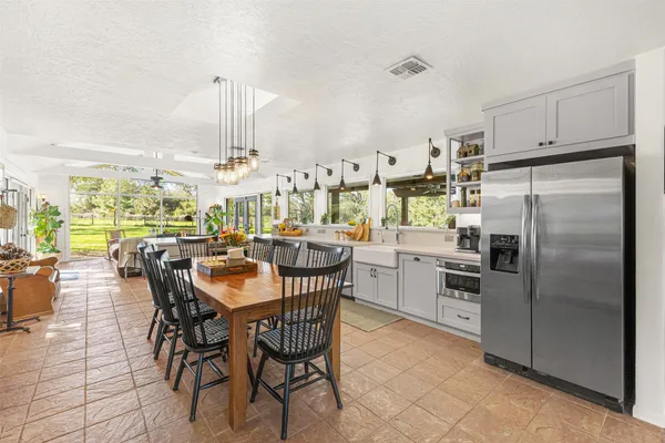a kitchen with stainless steel appliances a dining table chairs and a view of living room