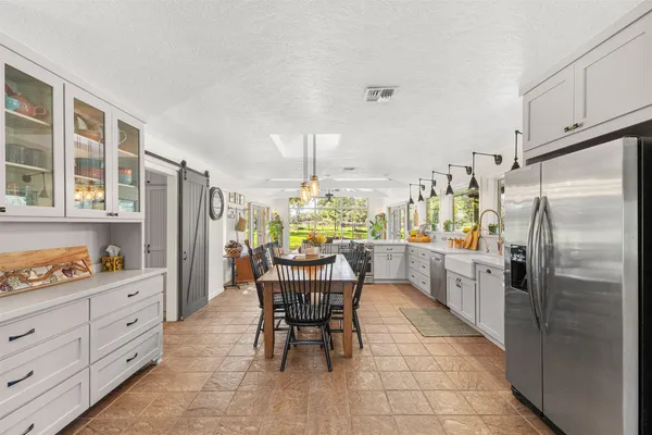 a kitchen with stainless steel appliances a table chairs and refrigerator