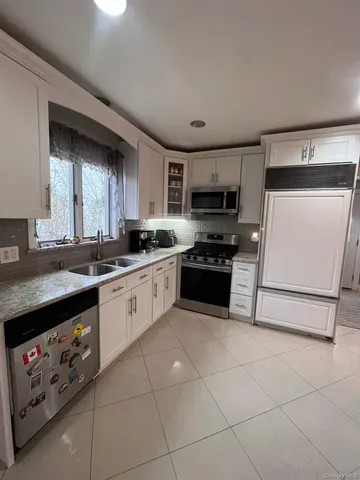 a large white kitchen with a stove a sink a microwave and cabinets