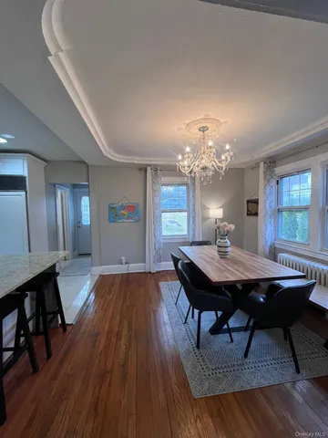 a dining room with wooden floor a chandelier a wooden table and chairs