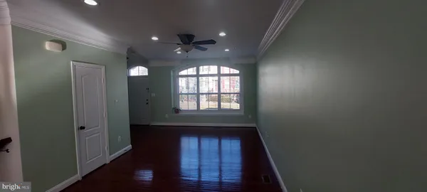 a view of hallway with wooden floor and fan