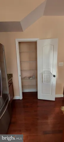 a view of an empty room with wooden floor and closet