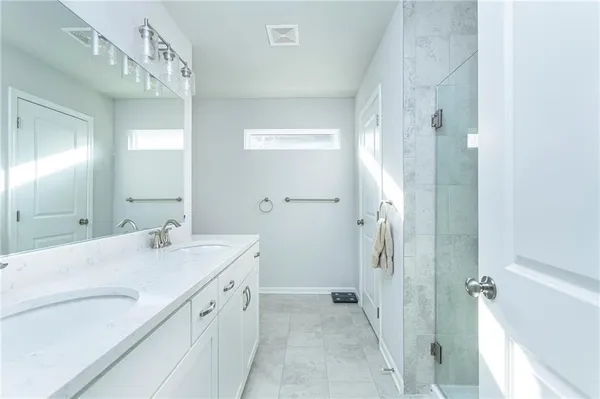 a bathroom with a double vanity sink mirror and shower