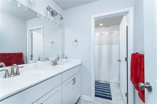 a en suite bathroom with a double vanity sink a mirror and shower