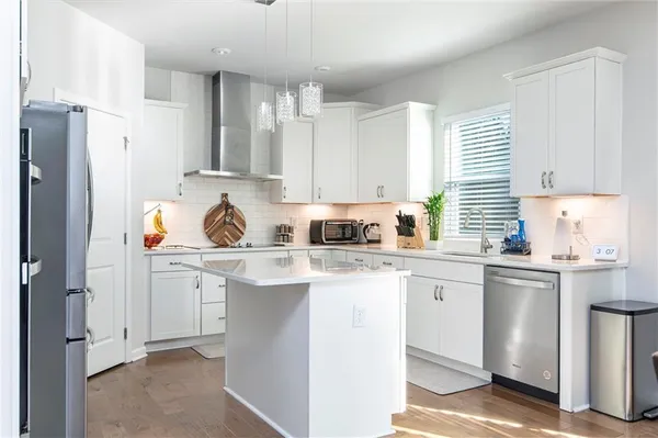 a kitchen with stainless steel appliances granite countertop a refrigerator sink and white cabinets