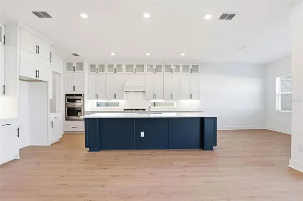a large white kitchen with kitchen island a sink stainless steel appliances and cabinets