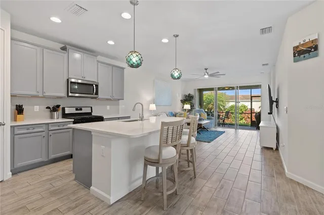 a kitchen with stainless steel appliances granite countertop a stove a sink a microwave a refrigerator and white cabinets with wooden floor