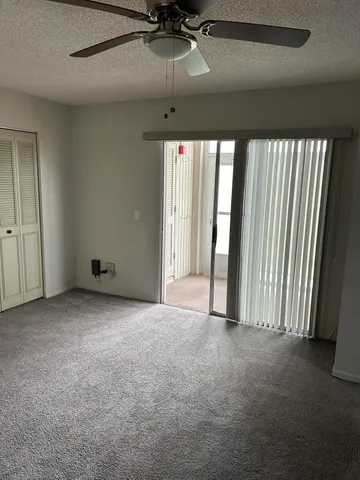 an empty room with windows and ceiling fan