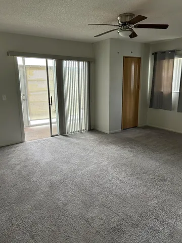 a view of a big room with windows and chandelier fan