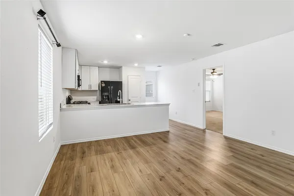 a view of a kitchen with a dishwasher a kitchen island hardwood floor and a window