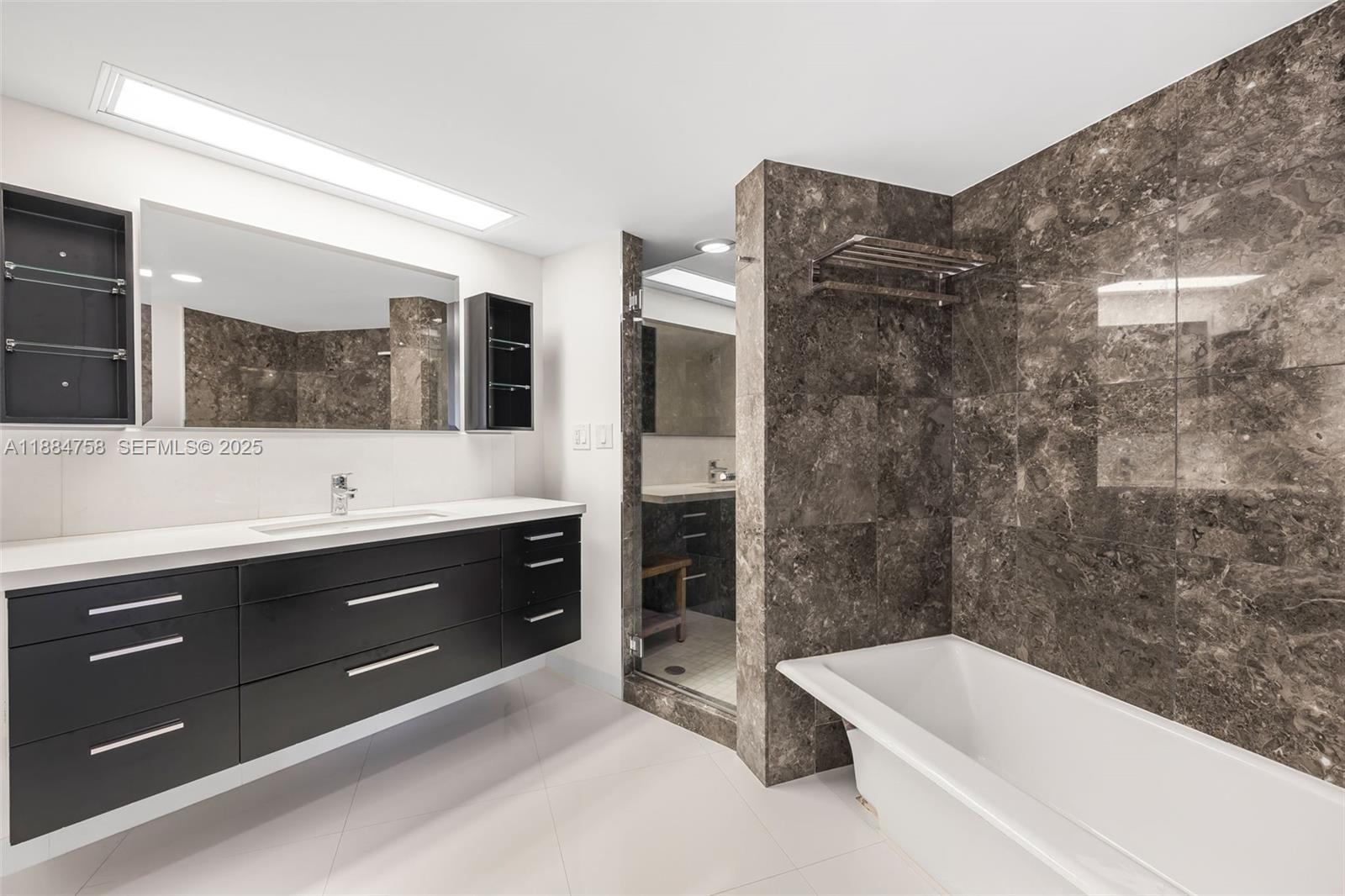 5660 Collins Avenue, Unit 8D Miami Beach, FL 33140 - Photo 20 of 41 a bathroom with a tub a sink and mirror