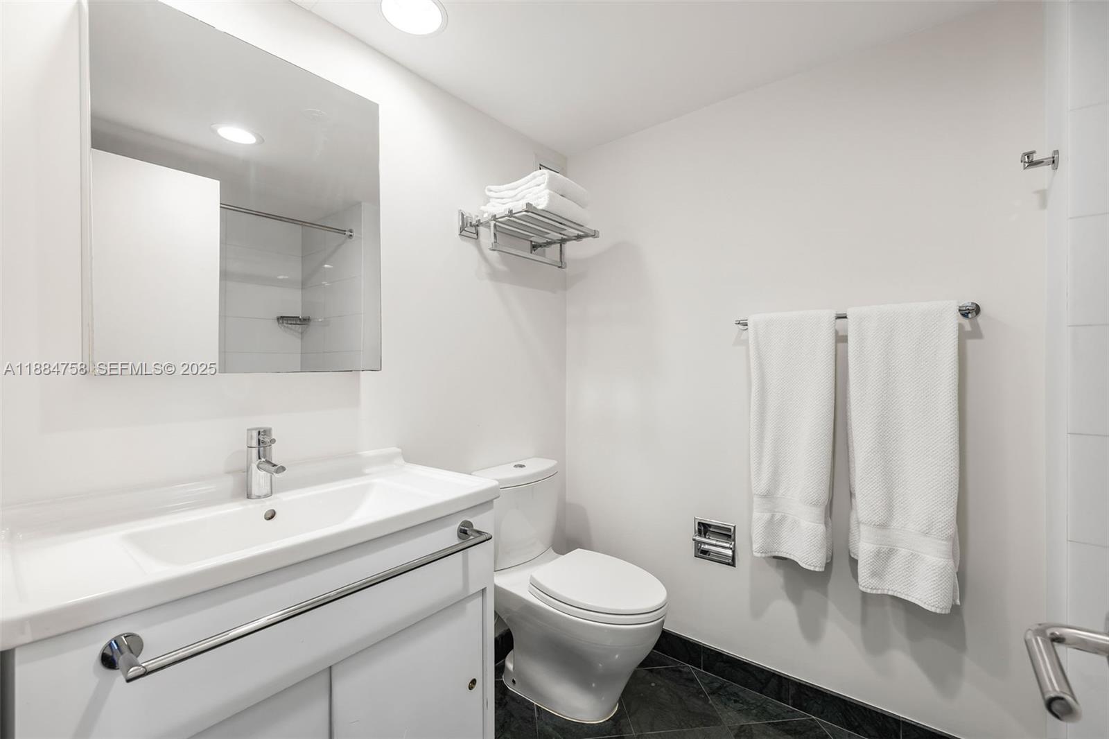 5660 Collins Avenue, Unit 8D Miami Beach, FL 33140 - Photo 26 of 41 a bathroom with a sink a toilet and a mirror