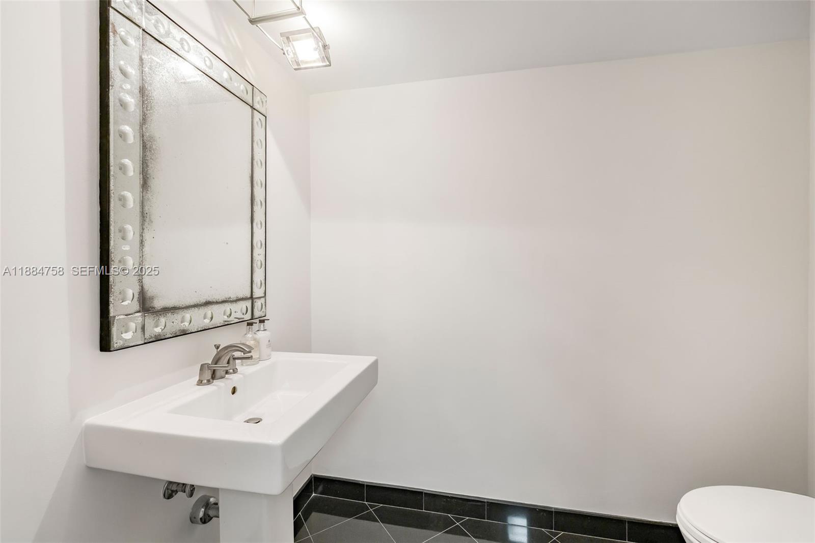 5660 Collins Avenue, Unit 8D Miami Beach, FL 33140 - Photo 34 of 41 a bathroom with a sink toilet and mirror