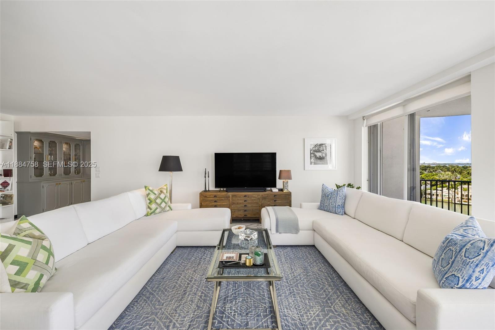 5660 Collins Avenue, Unit 8D Miami Beach, FL 33140 - Photo 5 of 41 a living room with furniture and a flat screen tv