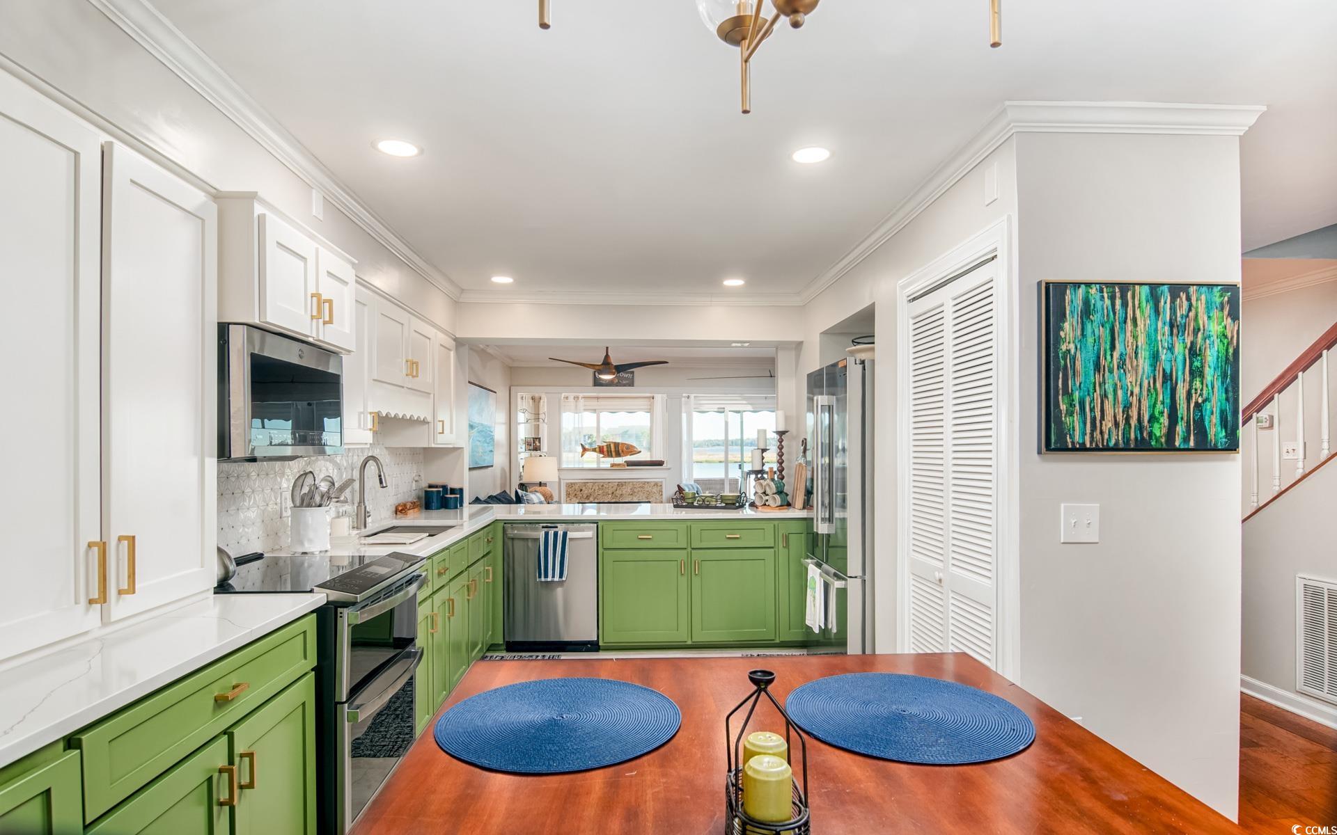 27 Pheasant Loop, Unit 293 Georgetown, SC 29440 - Photo 6 of 23 Kitchen featuring green cabinetry, a ceiling fan, stainless steel appliances, ornamental molding, and backsplash