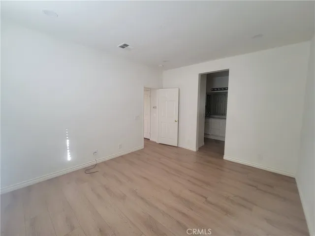 a view of an empty room with wooden floor and closet