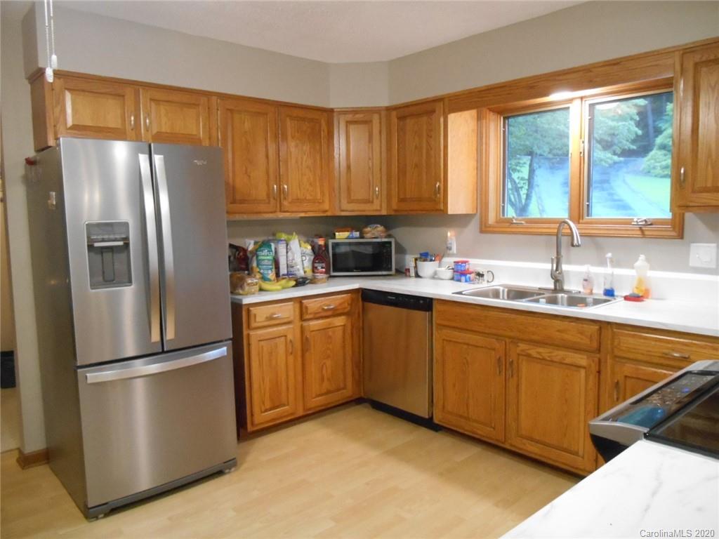 724 Laurel Ridge Road Columbus, NC 28722 - Photo 8 of 15 a kitchen with stainless steel appliances granite countertop a refrigerator a sink dishwasher a stove with white cabinets and wooden floor