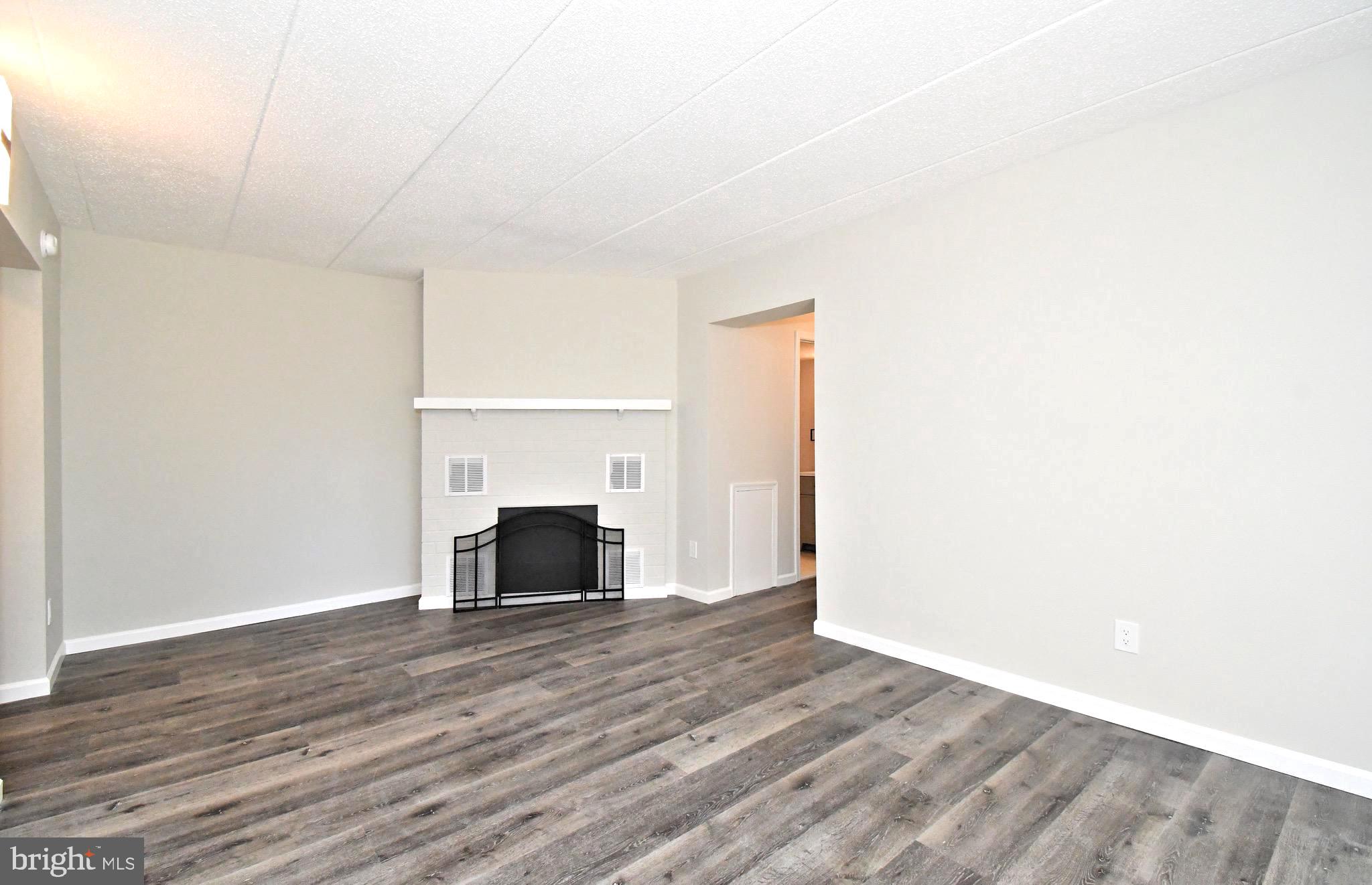 a view of a livingroom with wooden floor and a fireplace