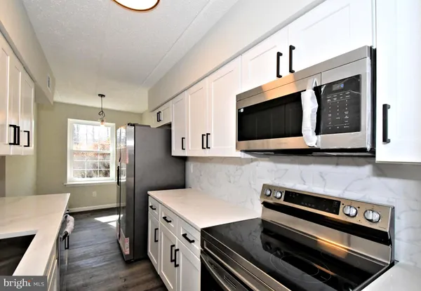 a kitchen with stainless steel appliances kitchen island a white stove top oven and sink