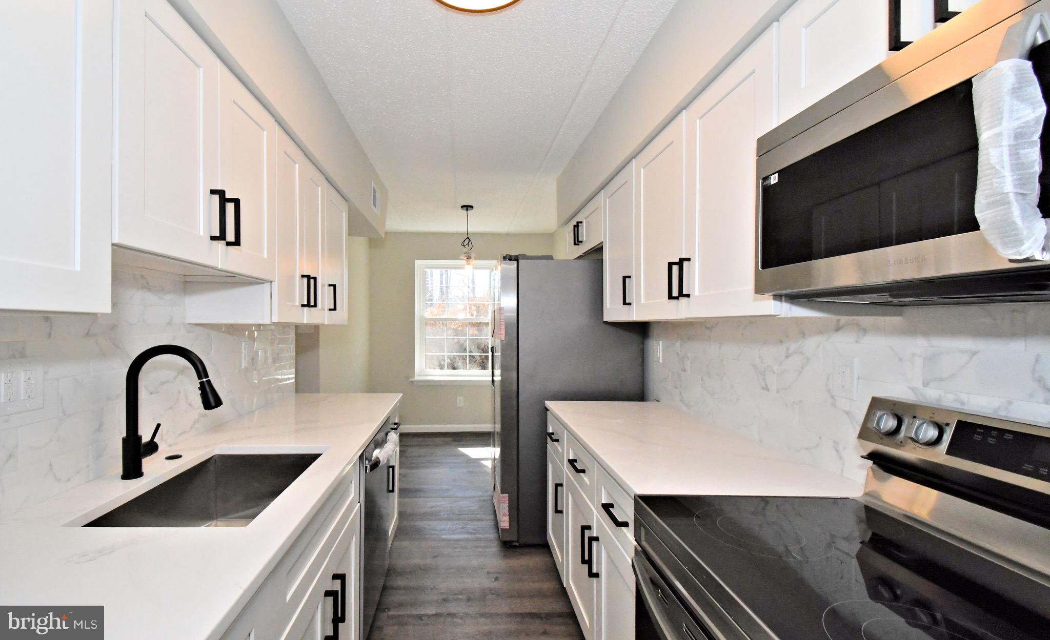 613 Washington Place, Unit 13 Chesterbrook, PA 19087 - Photo 35 of 64 a kitchen with stainless steel appliances kitchen island a white stove top oven and sink