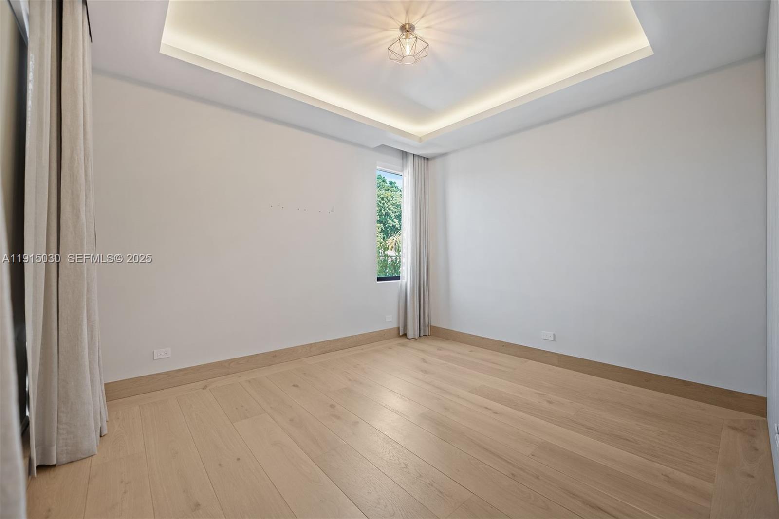 5831 Alton Road Miami Beach, FL 33140 - Photo 41 of 48 an empty room with a chandelier fan and windows
