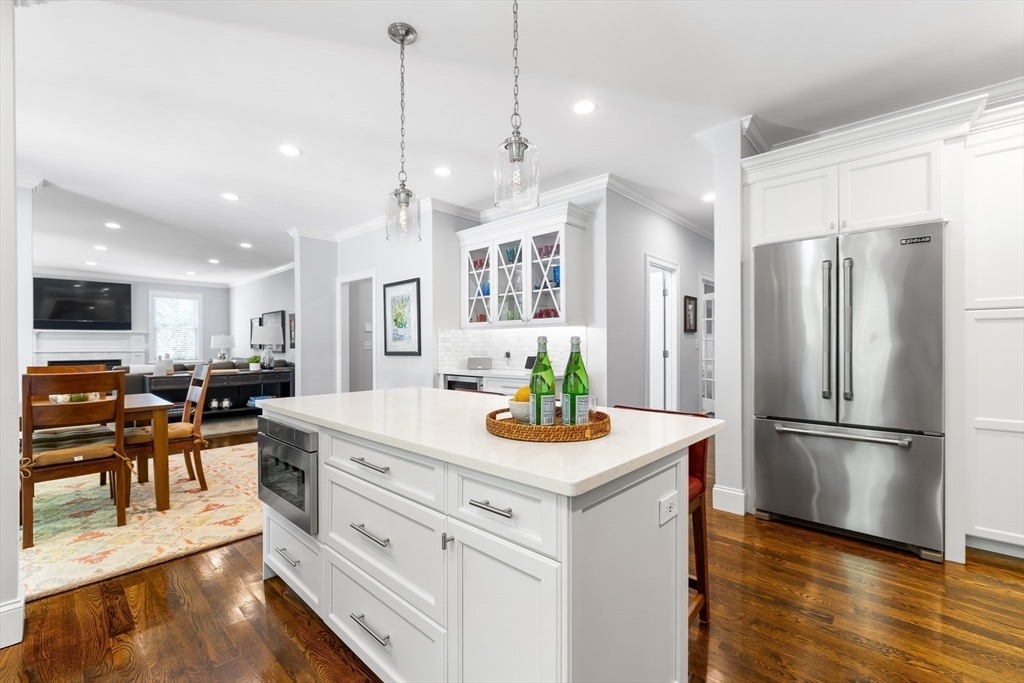 1332 Great Plain Avenue Needham, MA 02492 - Photo 8 of 42 a kitchen with stainless steel appliances granite countertop a refrigerator a microwave oven a dining table and chairs with wooden floor